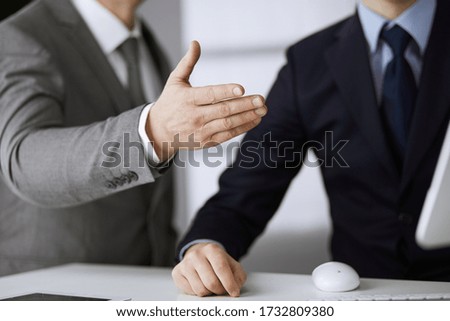 Business people using computer while working together in modern office. Unknown businessman or male entrepreneur with colleague at workplace. Teamwork and partnership concept