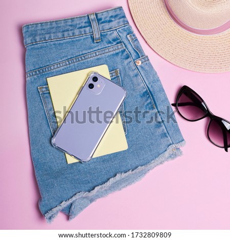 Purple iPhone 11 case mockup. Smart phone lies on shorts close-up, summer background, hat and sun glasses isolated on pink background, top view, clothing flat lay