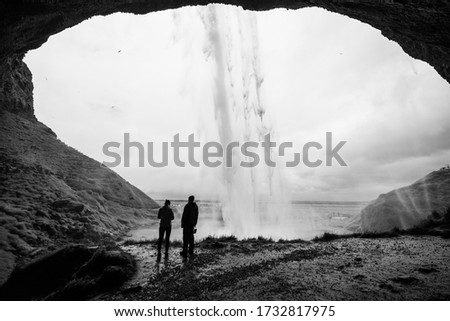 Visitors behind a waterfall in black and white