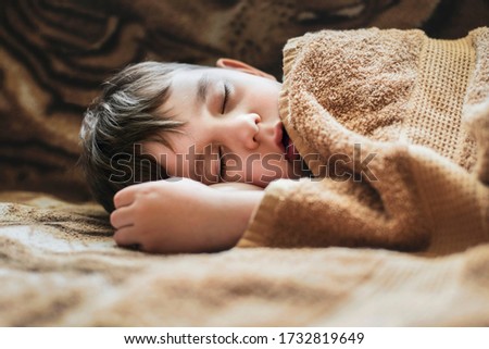 Portrait of a little boy sleeping soundly, the boy watched a cartoon after a long walk, ate and fell asleep. The boy rarely sleeps during the day but fell asleep today