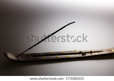 Incense stick on a wooden support with smoke on a white background
