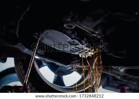 Car mechanic drain the old automatic transmission fluid (ATF) or gear oil at car garage for changing the oil in a gear box of car engine Royalty-Free Stock Photo #1732848212