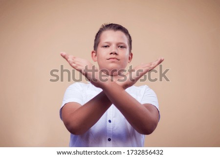 A portrait of kid boy showing stop gesture. Children and emotions concept 