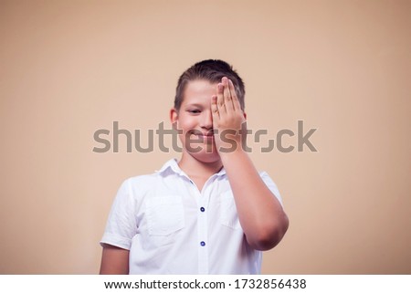 A portrait of kid boy covering half face with hand. Children and emotions concept 