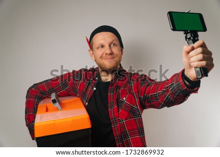 A builder is a man of Caucasian portrait as taking a selfie on a smartphone. The concept of plumbing photography for the blog