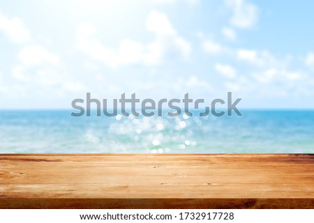 Wooden table top on blurred summer blue sea and sky background. Copy space for your display or montage product design. Royalty-Free Stock Photo #1732917728