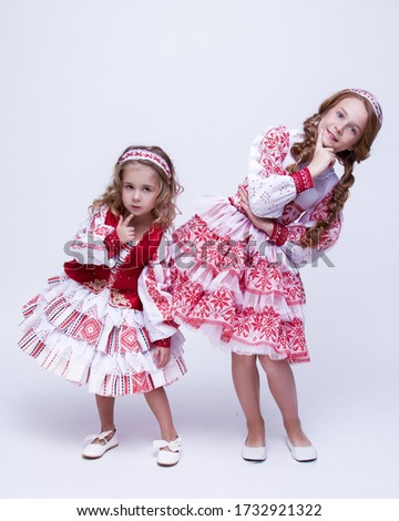 Girls in folk dresses have fun on a white background.