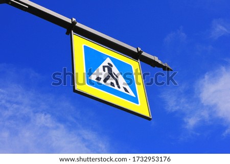 Pedestrian crossing point sign on city street isolated on blue sky background in Saint Petersburg, Russia. Sign with a man on crosswalk, safety symbol at crosswalk road