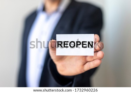 Reopening concept after the coronavirus pandemic. REOPEN word on a paper card in hands of a man in suit
