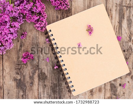 Top view of open school notebook with blank pages, on wooden old table background. Business, office or education concept with copy space. flat lay. Flowers lilac.