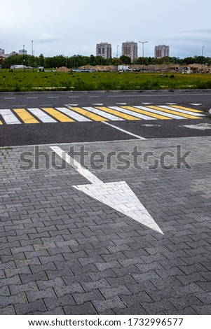 Road marking, an arrow indicating the direction of movement against the background of a pedestrian crossing