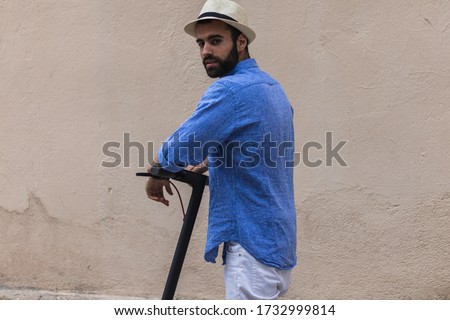 Young man with hat exploring the city on a electric scooter