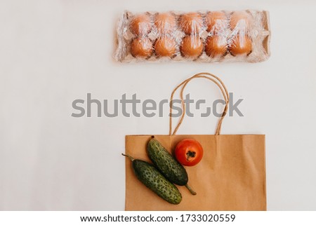 Paper bag with cucumbers, tomatoes, vegetable oil, eggs and canned goods isolated on white background.Food supplies crisis food stock for quarantine.Food delivery, Donation, coronavirus.Tape measure