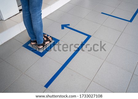 Ladies leg standing inside the social distance shopping line up marking in blue square box. Epidemic protection measures. Safe shopping, Social distancing concept