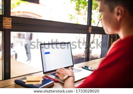 Young man skilled copywriter working distance on laptop computer while relaxing in coffee shop. Male developer web sites searching information via notebook 