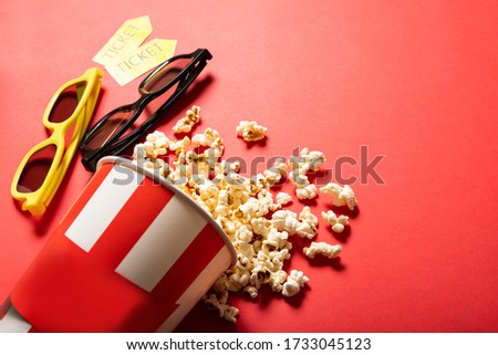 Paper cup with popcorn on a red background. Points and movie tickets