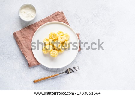  Curd and cheese dumplings served with berries and sour cream on a ceramic white plate. Traditional Ukrainian or Russian lazy dumplings (vareniki). Healthy Breakfast, top view.