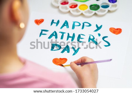 Child is drawing red heart with text Happy Father's Day on white paper. Happy Father's Day concept.