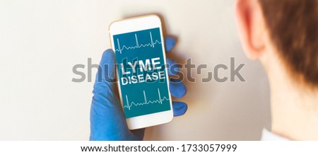 Hand in medical glove holding smartphone on white background. Blank screen with LYME DISEASE text.
