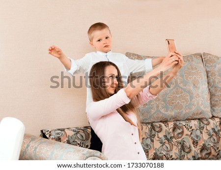 Mom and baby taking a selfie in a cozy living room. mom and son make funny faces and take pictures of themselves on camera