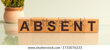 ABSENT word made with building blocks isolated on white. Potted flower in the background on the left.