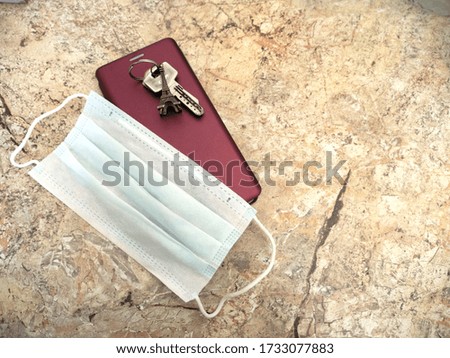 Medical mask, burgundy phone and house keys with Eiffel Tower keychain lie on a table, copy space for text