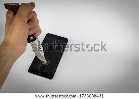 Phone screen crash or durability, endurance test concept with the hunter knife on the white background. It could be used in technological area, news, etc.
