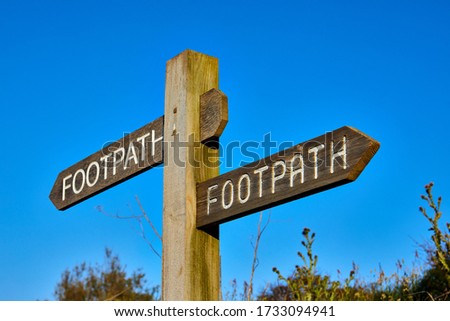 Image of a timber footpath sign with a clear blue sky, whth shallow sdepth of field, Selective focus.