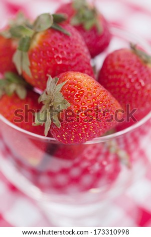 strawberry and cherry in a glass bowl on checkered fabric