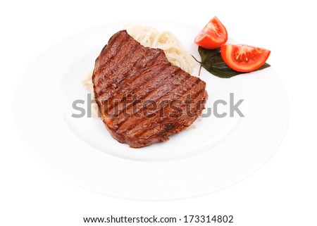 italian cuisine : grilled beef steak with pasta and tomatoes on basil leaf on plate isolated over white background