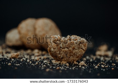 Cookies with milk and cookie crumbs all around placed on the black background in the small home studio with chocolate poured over them