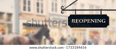 Reopening economy concept. Sign with word reopening hanging against open shop windows background. Restarting business after coronavirus lockdown. Economy recovery symbol
