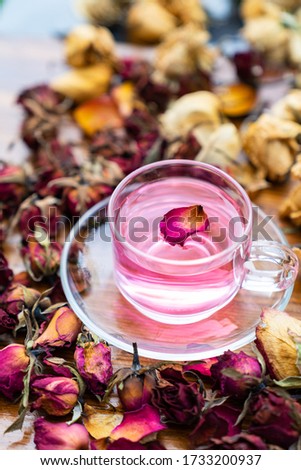 Organic tea rose made from tea  rose petals in a glass bowl on wooden rustic background around with dry rose petals