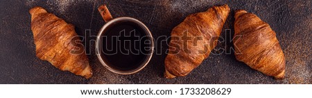 Coffee and croissant on stone background. French breakfast. Top view with copy space.