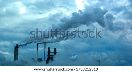 An aerial shot of a factory chimneys polluting the beautiful sky