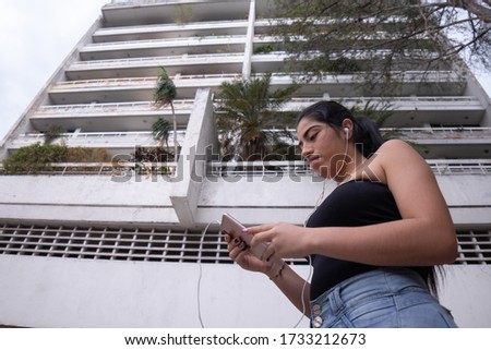 Woman listens to music through headphones connected to a mobile device