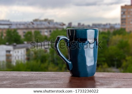 Blue mug on a wooden table in the patio against the background of the cityscape.