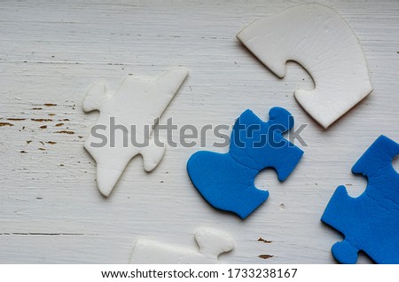 Unassembled puzzle pieces on white cracked paint. Blue and white puzzle pieces on an old wooden table. The concept of an old unsolved problem. Psychological trauma in childhood.