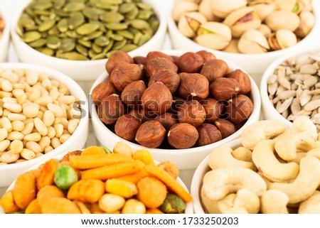 The various kind of nuts and seeds in the white ceramic bowls.