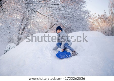 Winter fun in the city. A boy rides on a slide of ice.