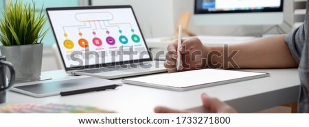 Cropped shot of graphic designer working on infographic project with mock-up tablet and laptop Royalty-Free Stock Photo #1733271800