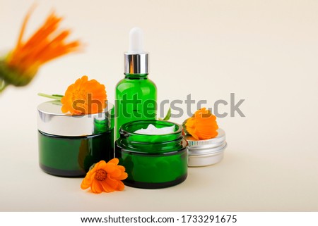 Cream for face and body. Green jar with calendula cream and orange flowers.