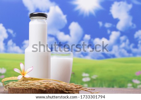 Bottle of fresh milk on the wooden floor. The background is a green meadow. In the morning, there is sunshine