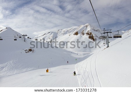 Chairlift hovering above groomed ski slope at ski resort.