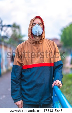 A young Caucasian man in mask walking through a park. First walks of the uncontrolled Covid-19 pandemic