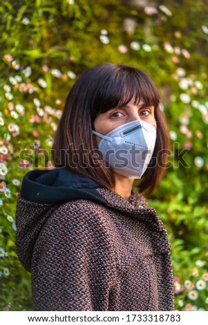 A young woman with a mask on her first walks in mistrust. First walks of the uncontrolled Covid-19 pandemic