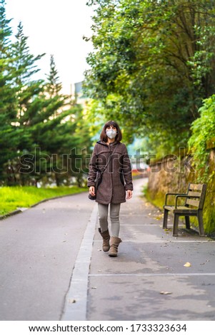 A Caucasian brunette with short hair and a protective mask for the coronavirus. First walks of the uncontrolled Covid-19 pandemic