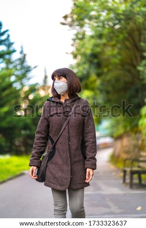 Lifestyle of a Caucasian brunette with short hair and mask walking in a park. First walks of the uncontrolled Covid-19 pandemic