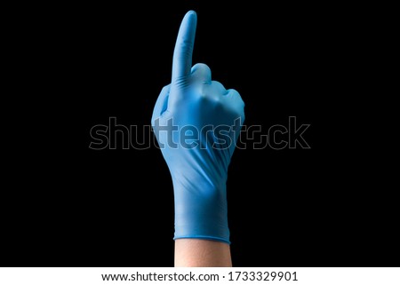 Doctor's hand in sterile medical gloves pointing up isolated on black background with clipping path. Concept of protection against pandemic and viruses.
