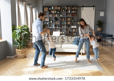 Overjoyed young family with little preschooler daughters have fun playing together in living room, happy Caucasian parents dance swirl engaged in funny activity with small girls children at home Royalty-Free Stock Photo #1733354978
